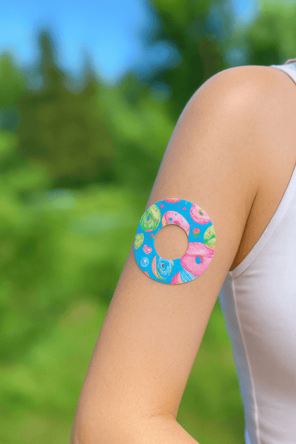 Färgglad Donut CGM sensoröverdrag för Freestyle Libre 1 & 2 på arm, gjord av mjukt non-woven material. Hudvänlig och slitstark.